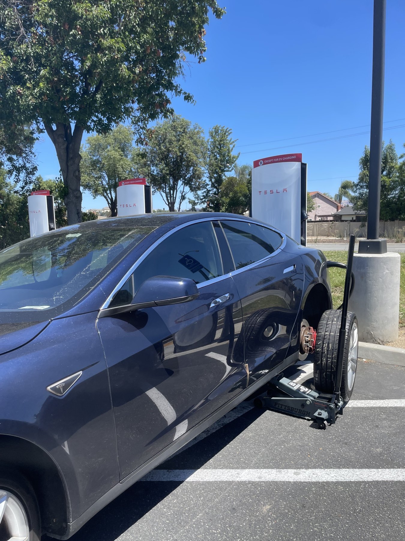 A Tesla raised on a jack at a charging station during a mobile tire service call