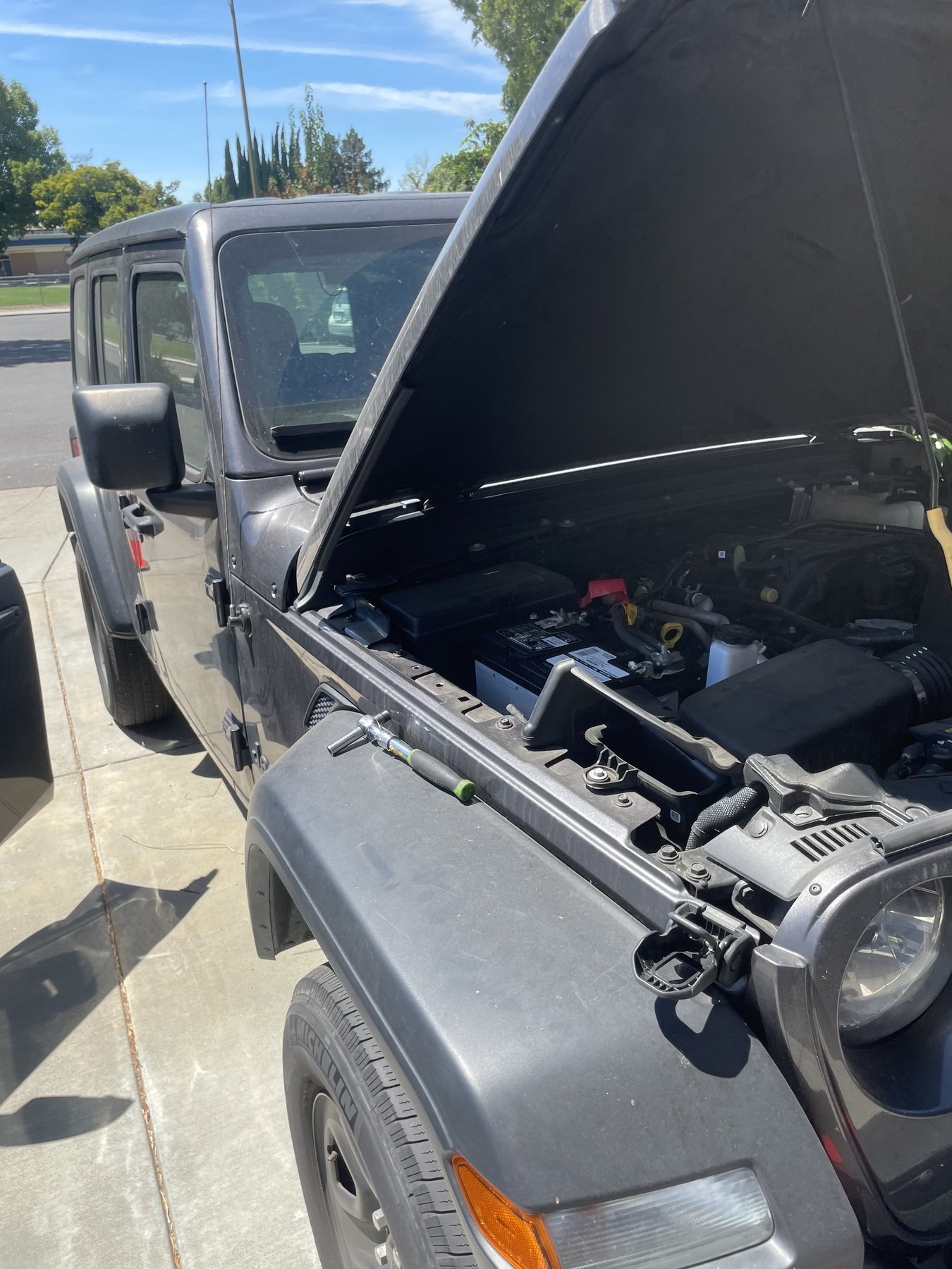 A Jeep with the hood raised during a mobile battery replacement